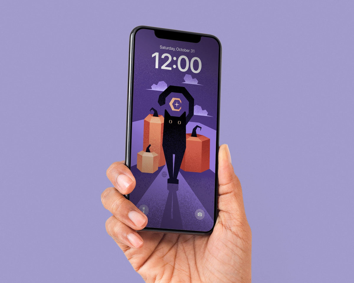 A hand holding a black smartphone against a solid lavender-purple background. The phone screen displays a digital lock screen wallpaper featuring a stylized illustration of a black cat and some pumpkins